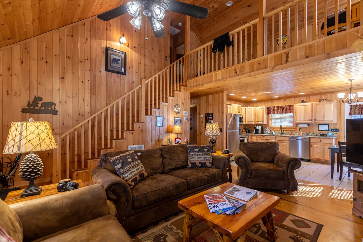 This image captures a warm, welcoming living space featuring a rustic wooden staircase, plush couches, and decor that blends comfort with mountain character. Ample seating invites groups to gather for relaxation or games, and the cozy atmosphere suggests a perfect setting for evening conversations after a day’s adventures.