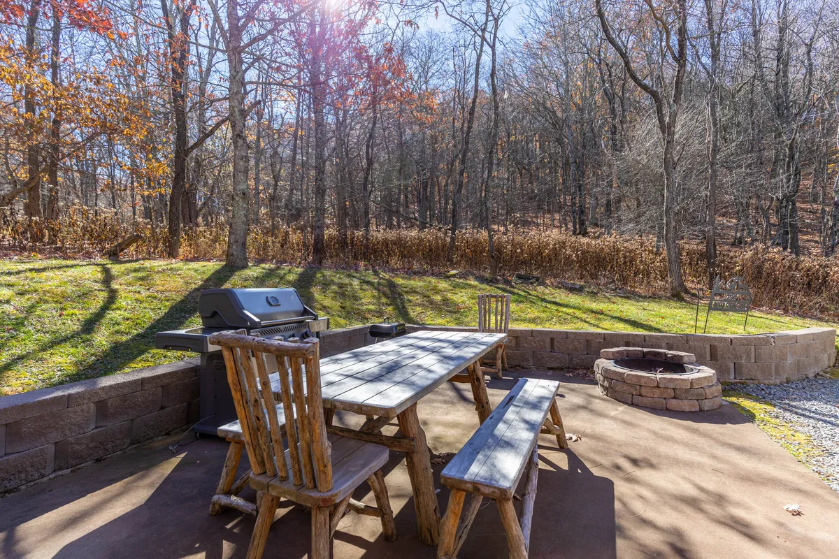 A spacious outdoor area features a grill, picnic table, and a cozy fire pit, creating a perfect environment for barbecues, outdoor dining, and gathering with friends and family. The scene is relaxed, with enough space for kids to play and adults to unwind.